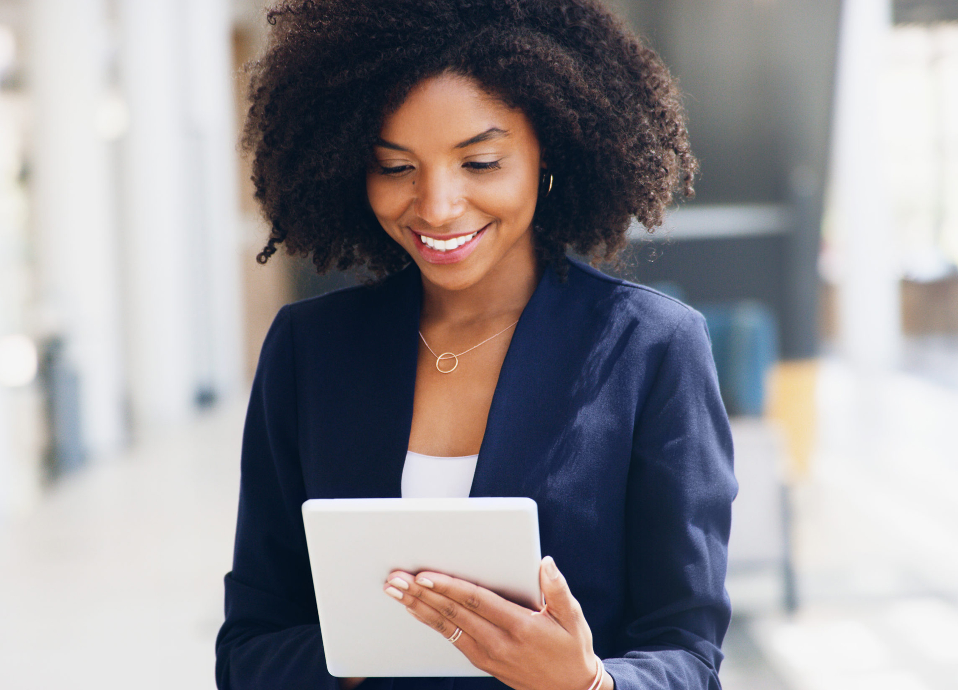 Cropped shot of an attractive young businesswoman standing alone and using a tablet while in the office during the day